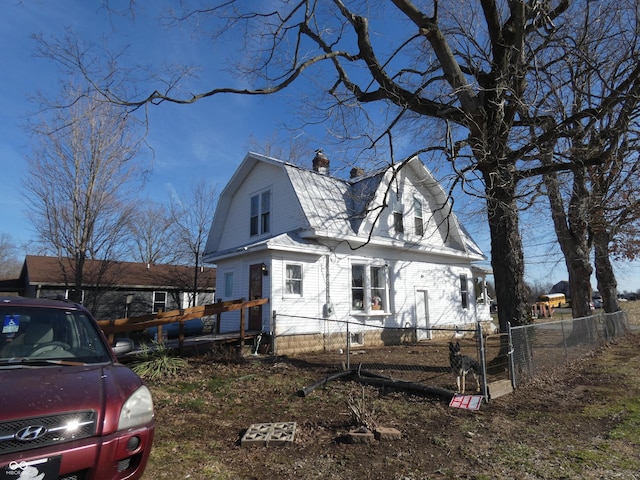 view of front of home featuring a gate, a chimney, fence, and a gambrel roof