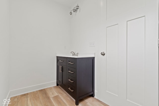 bathroom with baseboards, wood finished floors, and vanity