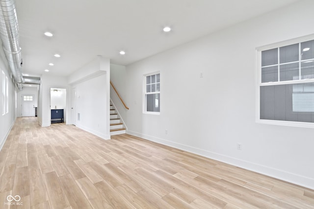 unfurnished living room featuring recessed lighting, stairway, baseboards, and light wood finished floors