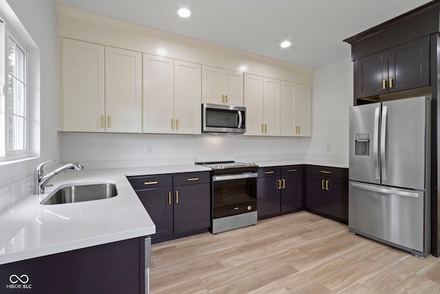 kitchen with light wood finished floors, recessed lighting, a sink, light countertops, and appliances with stainless steel finishes