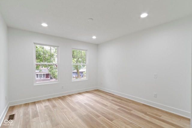 spare room featuring light wood-style floors, visible vents, and baseboards