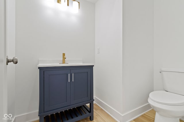 bathroom featuring toilet, vanity, baseboards, and wood finished floors