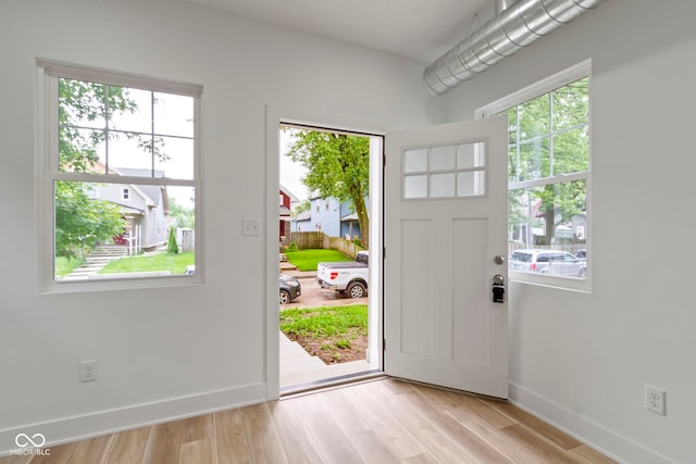 entryway with a healthy amount of sunlight, light wood-type flooring, and baseboards