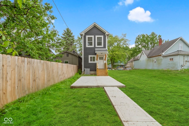 back of property featuring entry steps, fence, a lawn, and central AC