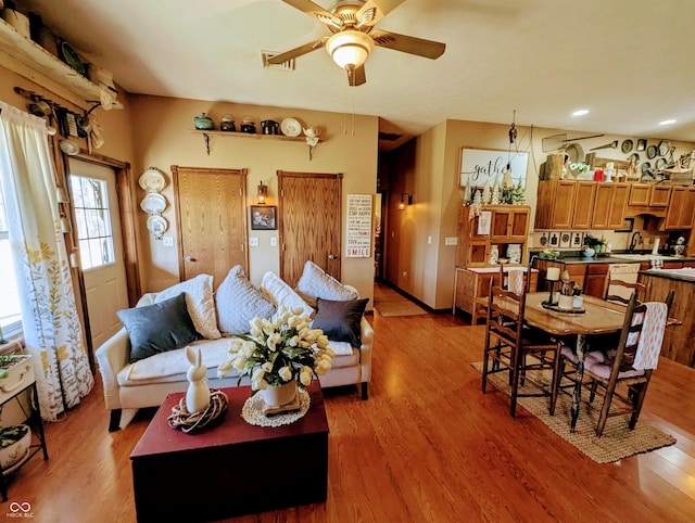 living room with ceiling fan, visible vents, and light wood-style floors