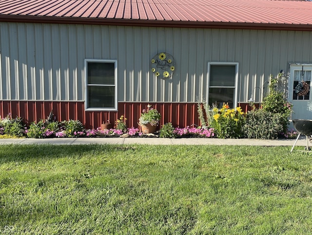 entrance to property with board and batten siding, metal roof, and a lawn