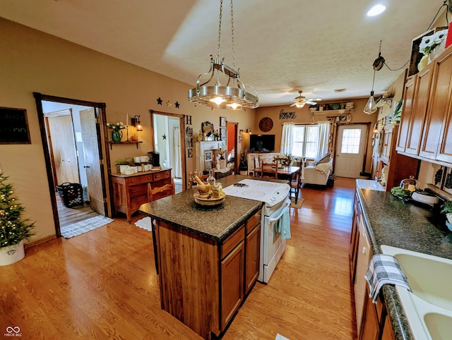 kitchen featuring brown cabinets, white electric stove, light wood finished floors, dark countertops, and open floor plan