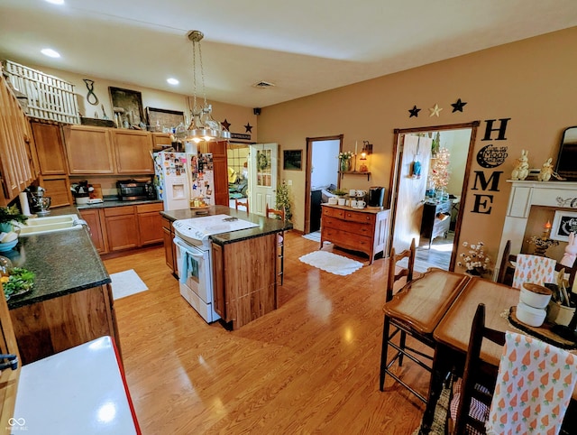 kitchen featuring white appliances, light wood finished floors, visible vents, a center island, and a sink