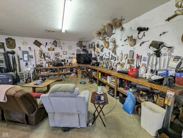 interior space featuring a textured ceiling, concrete floors, a workshop area, and visible vents