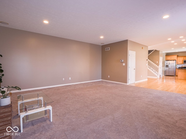 unfurnished room featuring recessed lighting, light colored carpet, stairway, and baseboards