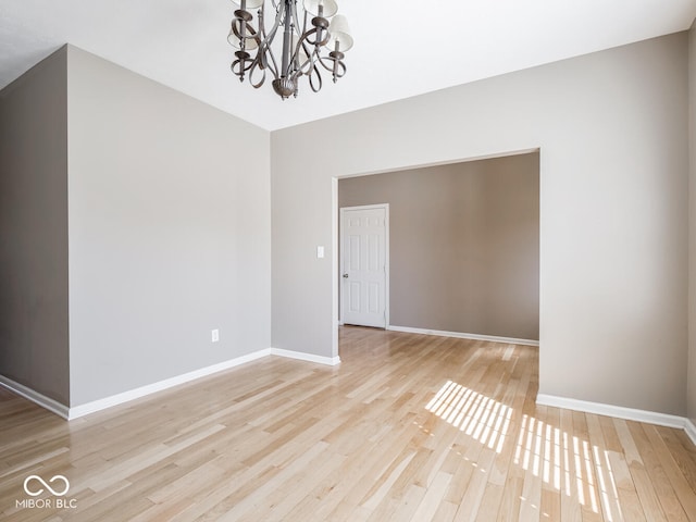 unfurnished room featuring baseboards, wood finished floors, and a notable chandelier