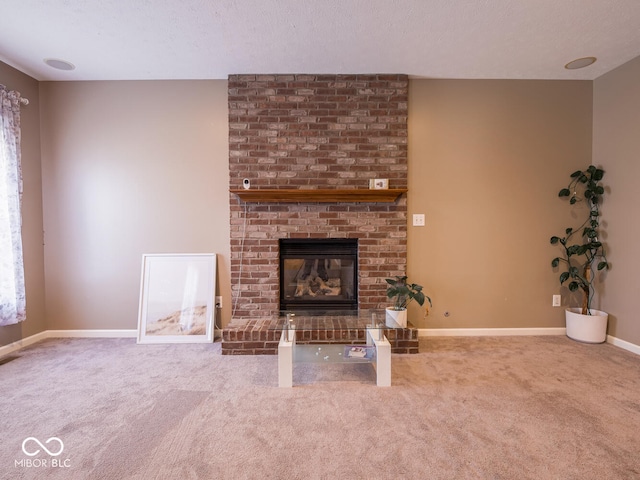 unfurnished living room featuring a brick fireplace, carpet, baseboards, and a textured ceiling