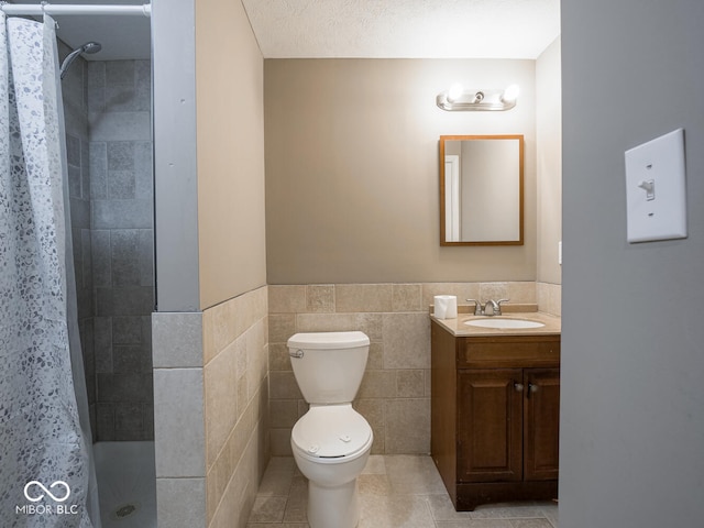 bathroom featuring tile patterned flooring, toilet, vanity, tile walls, and a tile shower