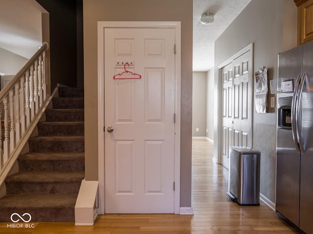 stairs with a textured ceiling, wood-type flooring, and baseboards