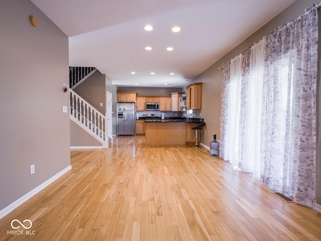 kitchen featuring light wood-type flooring, dark countertops, baseboards, and stainless steel appliances