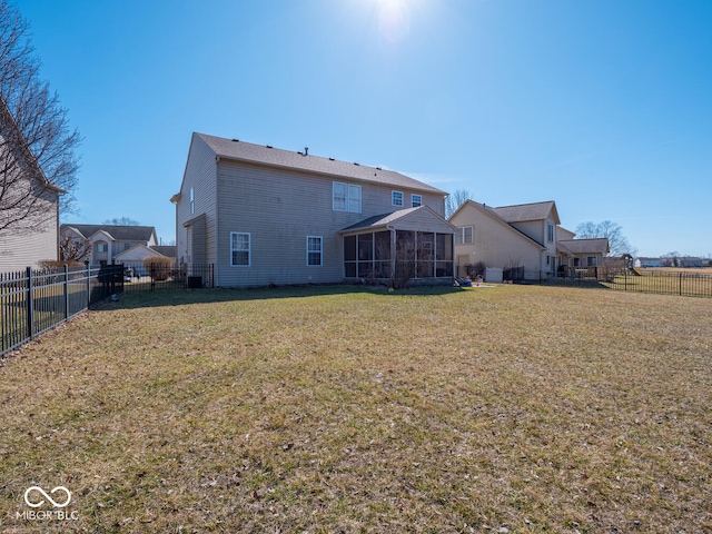 rear view of house with a lawn, a fenced backyard, and a sunroom