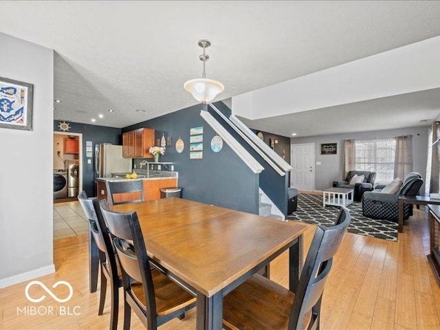 dining space with stairs, baseboards, and light wood finished floors