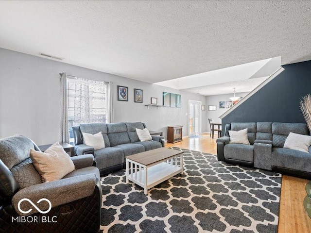 living area with visible vents, a healthy amount of sunlight, a textured ceiling, and wood finished floors