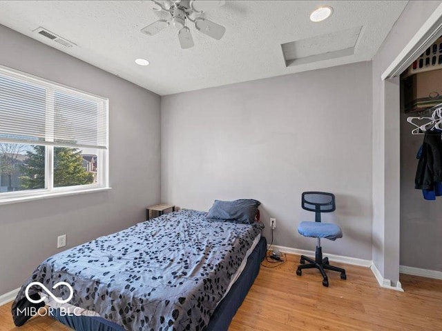 bedroom featuring visible vents, baseboards, attic access, and wood finished floors