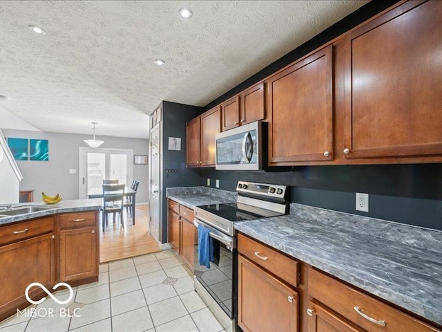 kitchen with stainless steel appliances, light tile patterned flooring, and brown cabinetry