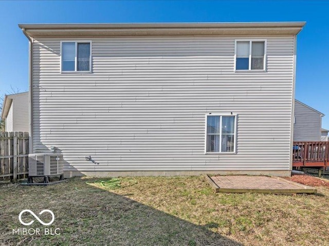 back of property with a yard, fence, and central AC