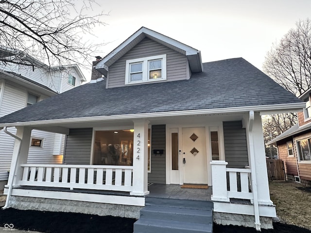 bungalow featuring covered porch and roof with shingles