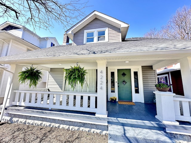 bungalow-style house with a porch and roof with shingles