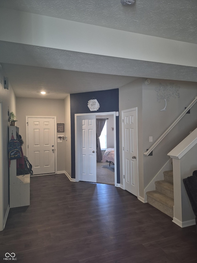 foyer with a textured ceiling, stairs, and wood finished floors