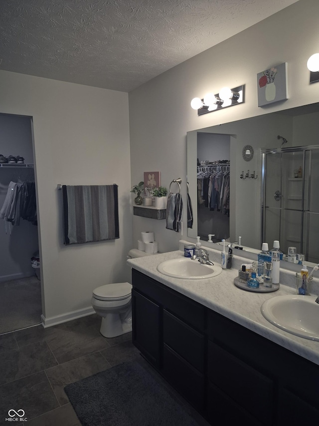 full bathroom featuring a stall shower, a sink, a textured ceiling, and double vanity