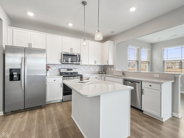 kitchen featuring stainless steel appliances, a peninsula, a sink, and light countertops