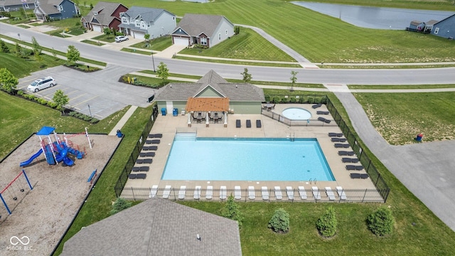 pool with a community hot tub, playground community, a water view, fence, and a patio area