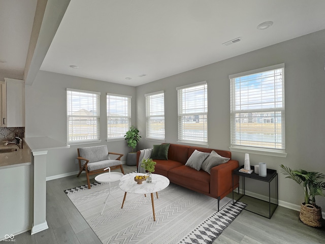 living room with light wood-style flooring, visible vents, and baseboards