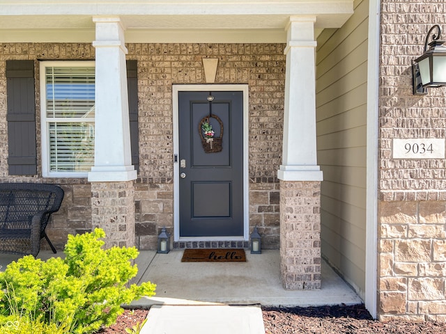 entrance to property with a porch and brick siding