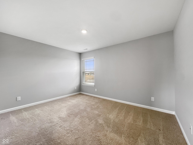 empty room featuring carpet and baseboards