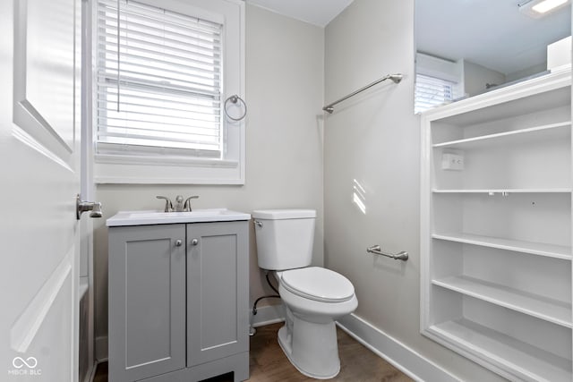 bathroom with baseboards, plenty of natural light, toilet, and wood finished floors