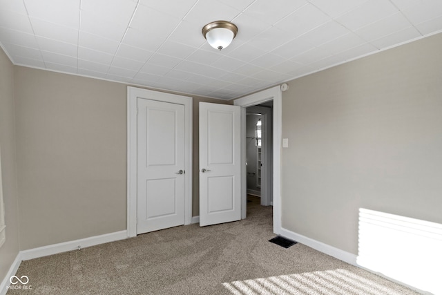 unfurnished bedroom with carpet flooring, visible vents, and baseboards