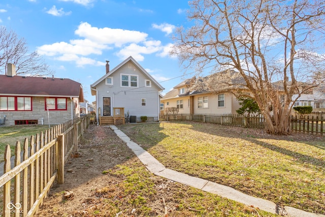 rear view of property featuring a fenced backyard and a lawn