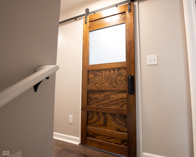 interior space featuring a barn door, baseboards, and dark wood finished floors