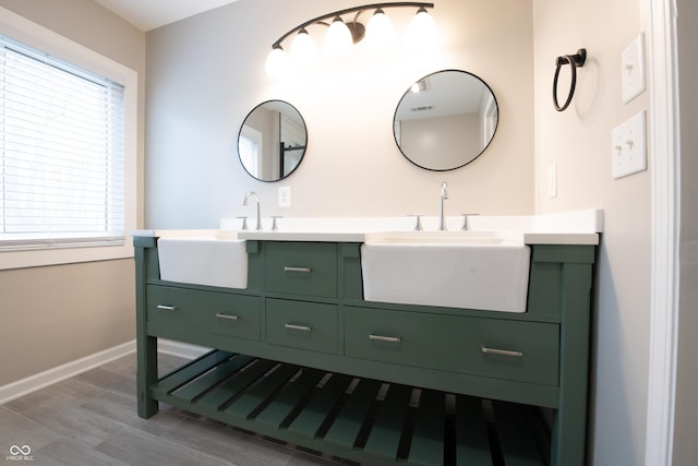 full bath featuring double vanity, baseboards, and a sink