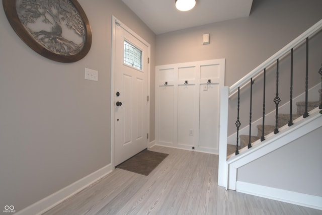 entryway featuring stairway, wood finished floors, and baseboards