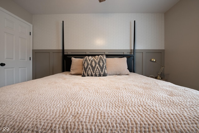 bedroom with wainscoting and wallpapered walls