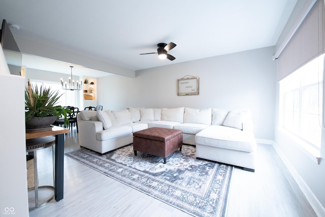 living area with ceiling fan with notable chandelier, baseboards, and wood finished floors