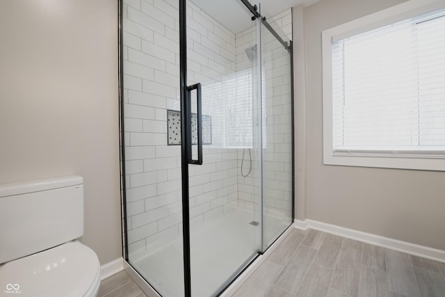 full bathroom with baseboards, a shower stall, and toilet