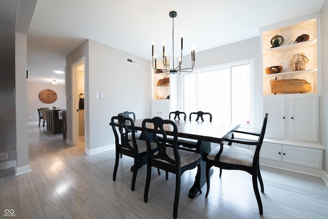 dining space featuring visible vents, a notable chandelier, baseboards, and wood finished floors