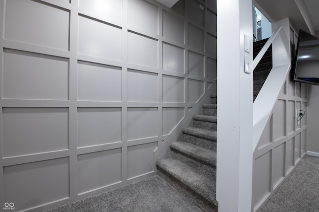 stairway featuring carpet and a decorative wall