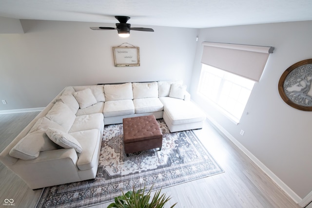 living area featuring wood finished floors, a ceiling fan, and baseboards