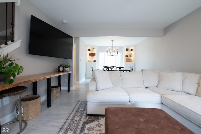 living area with baseboards, light wood-style flooring, and a notable chandelier