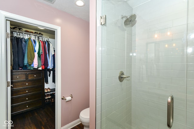 full bath with a textured ceiling, wood finished floors, a stall shower, and a walk in closet