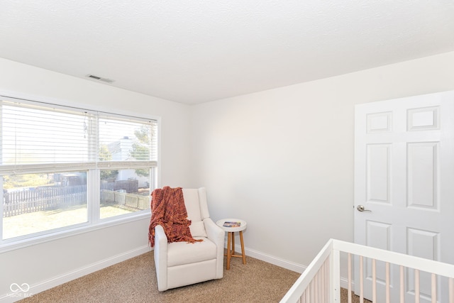 bedroom with light colored carpet, visible vents, a textured ceiling, a crib, and baseboards