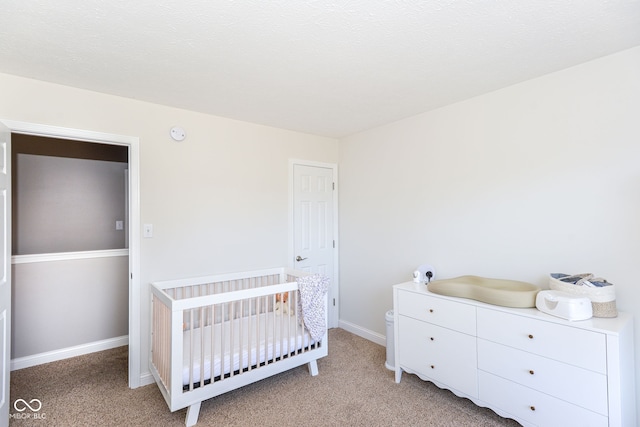 bedroom featuring baseboards, a nursery area, and light colored carpet